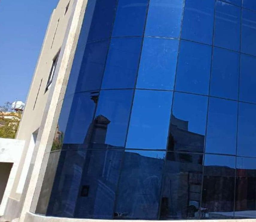 واجهة منحنية من الزجاج الأزرق العاكس محاطة بتكسية حجرية