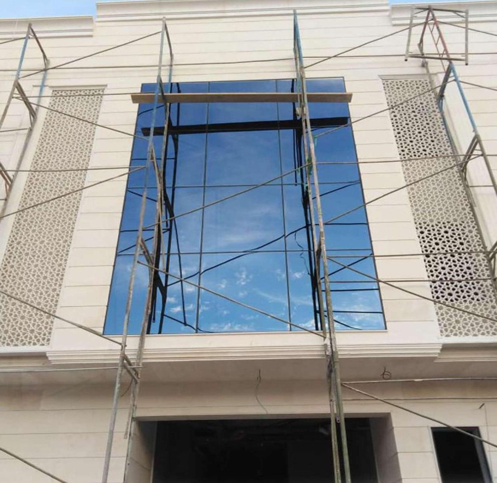 فتحة واجهة زجاجية مرتفعة في مبنى مكسو بالحجر مع السقالات أثناء التركيب